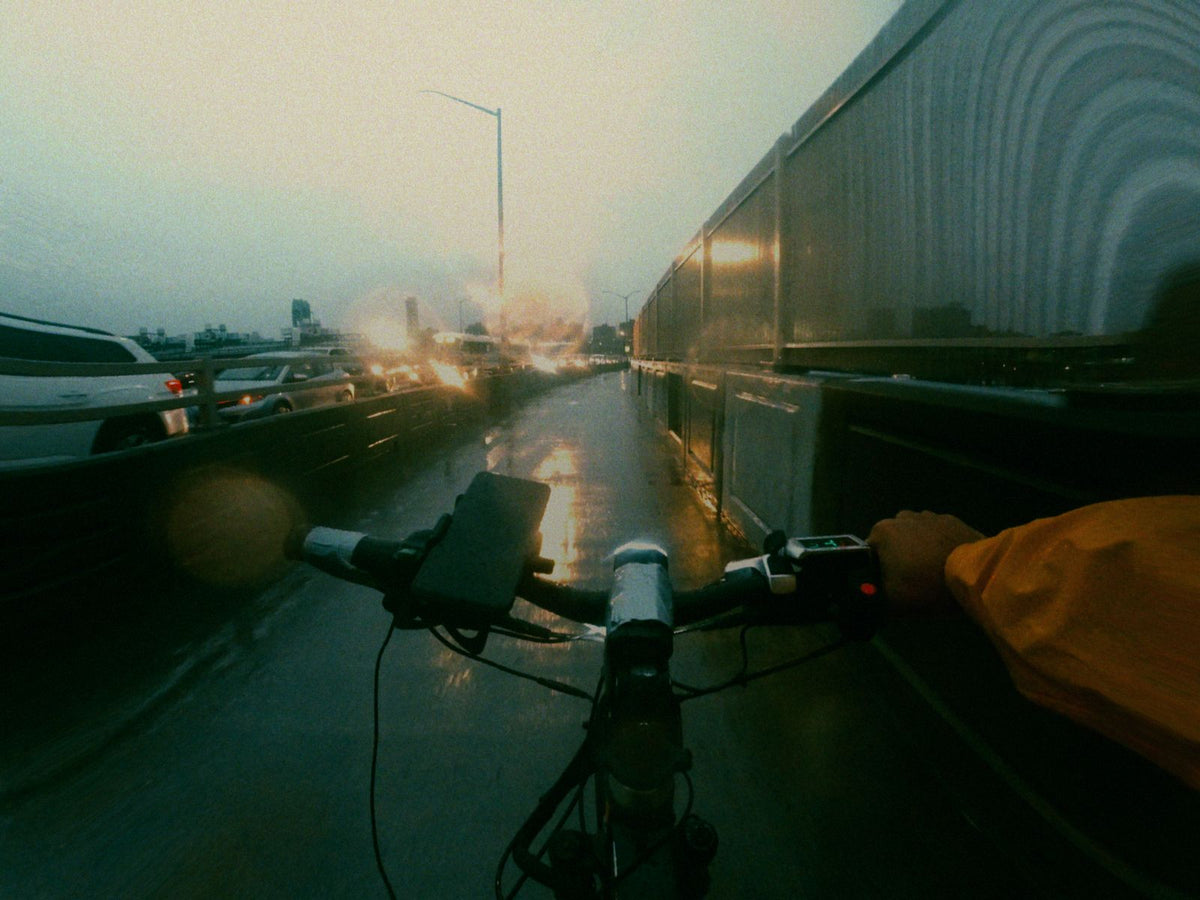 Cycliste sur une piste cyclable mouillée un jour de pluie, feux de circulation flous en arrière-plan
