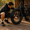 Un homme installe un antivol pliant sur la roue avant d'un Fat Bike électrique afin de sécuriser son vélo contre le vol.
