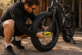Un homme installe un cadenas antivol bloque-disque jaune sur le disque de frein avant d'un Fat Bike électrique pour sécuriser son vélo avant de le stationner.