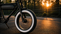 Gros plan d'un pneu Fat Bike 20x4 à flanc blanc monté sur un vélo électrique, photographié au coucher du soleil pour mettre en valeur son design et son adhérence.
