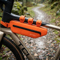 Pochette de cadre de vélo SYKELL orange montée sur un vélo gravel lors d'une sortie sous la pluie.