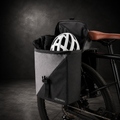 Sacoche double porte-bagages pour vélo électrique avec casque et vêtements illustrant la capacité de rangement.